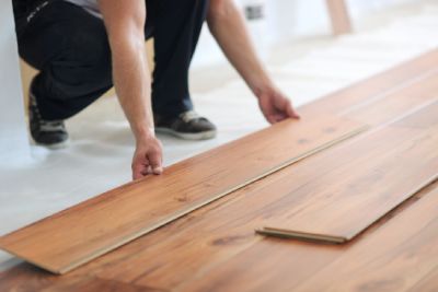 Une personne pose un parquet en bois